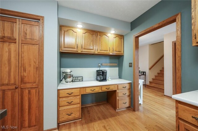 kitchen featuring built in desk, backsplash, and light hardwood / wood-style floors