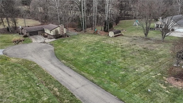 view of yard with aphalt driveway, an outbuilding, and a carport