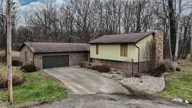 view of front of home featuring driveway, an attached garage, and a chimney