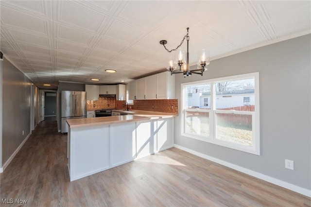 kitchen featuring sink, tasteful backsplash, appliances with stainless steel finishes, kitchen peninsula, and white cabinets