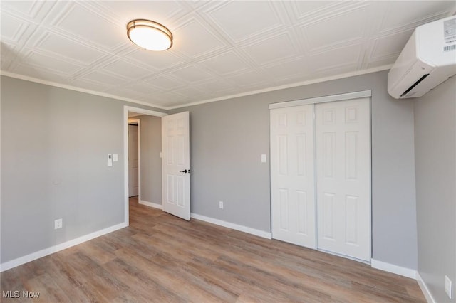 unfurnished bedroom with a wall mounted air conditioner, light wood-type flooring, and a closet