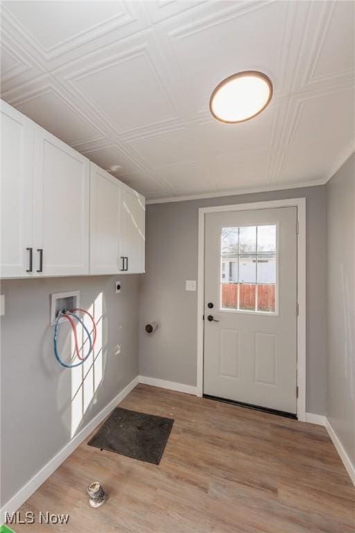 washroom featuring washer hookup, crown molding, light hardwood / wood-style floors, and cabinets