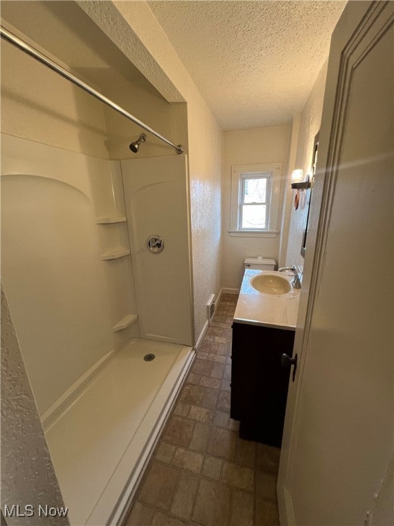 bathroom with vanity, a textured ceiling, and a shower