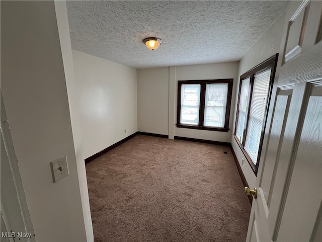 carpeted empty room featuring a textured ceiling