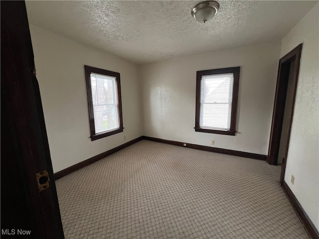 carpeted empty room featuring a textured ceiling