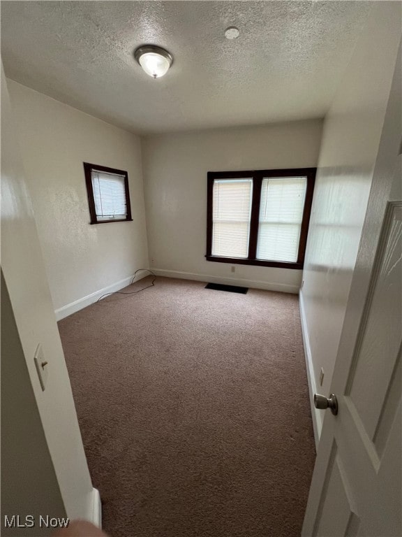 unfurnished room with carpet floors and a textured ceiling