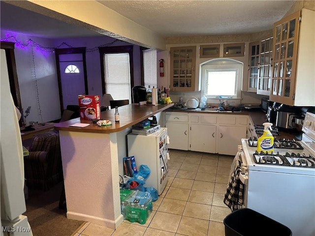 kitchen with white cabinetry, white range with gas cooktop, light tile patterned floors, and a textured ceiling