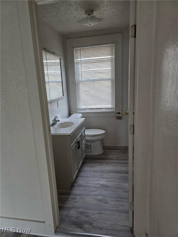 bathroom with hardwood / wood-style flooring, vanity, toilet, and a textured ceiling