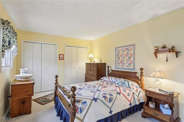 carpeted bedroom featuring a textured ceiling and multiple closets