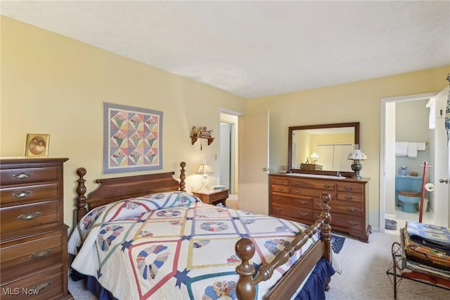 bedroom featuring connected bathroom and light carpet