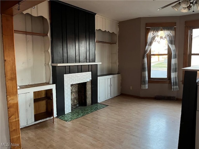 unfurnished living room with ceiling fan, a fireplace, and light hardwood / wood-style flooring