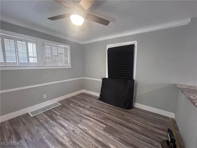 empty room featuring dark hardwood / wood-style flooring, ceiling fan, and a textured ceiling