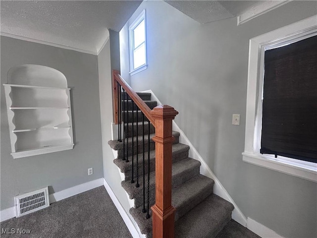 staircase featuring carpet flooring and a textured ceiling