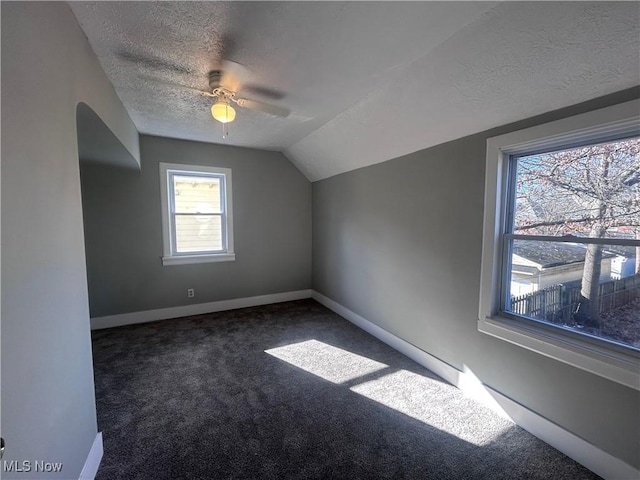 bonus room with lofted ceiling, ceiling fan, dark carpet, and a textured ceiling