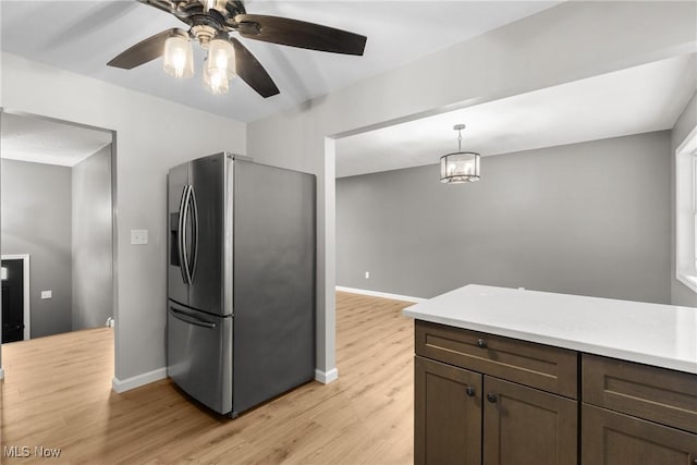 kitchen with decorative light fixtures, stainless steel fridge with ice dispenser, dark brown cabinets, and light wood-type flooring