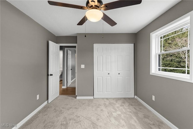 unfurnished bedroom with light colored carpet, ceiling fan, and a closet