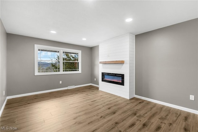 unfurnished living room with wood-type flooring and a fireplace