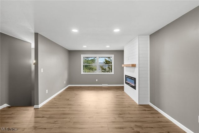 unfurnished living room featuring a fireplace and light hardwood / wood-style floors