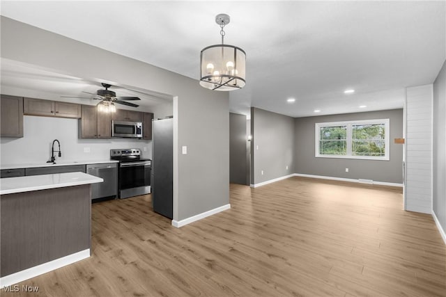 kitchen with hanging light fixtures, dark brown cabinets, light hardwood / wood-style floors, and appliances with stainless steel finishes