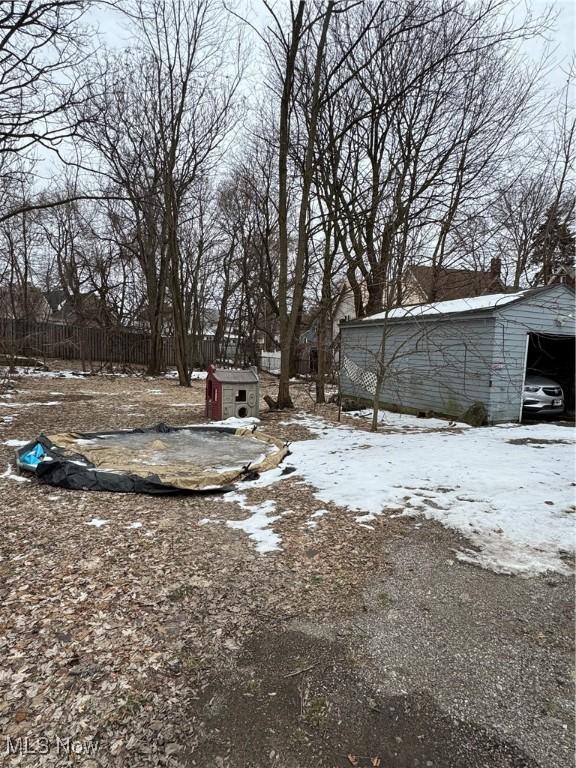 yard covered in snow with a garage and a storage unit