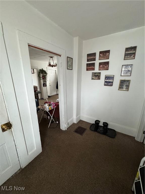 hall featuring dark colored carpet