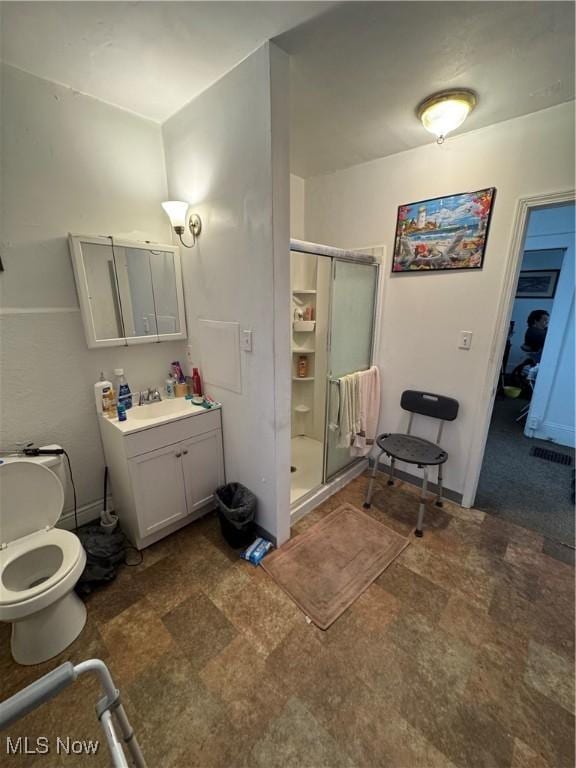 bathroom with a shower with door, vanity, and toilet