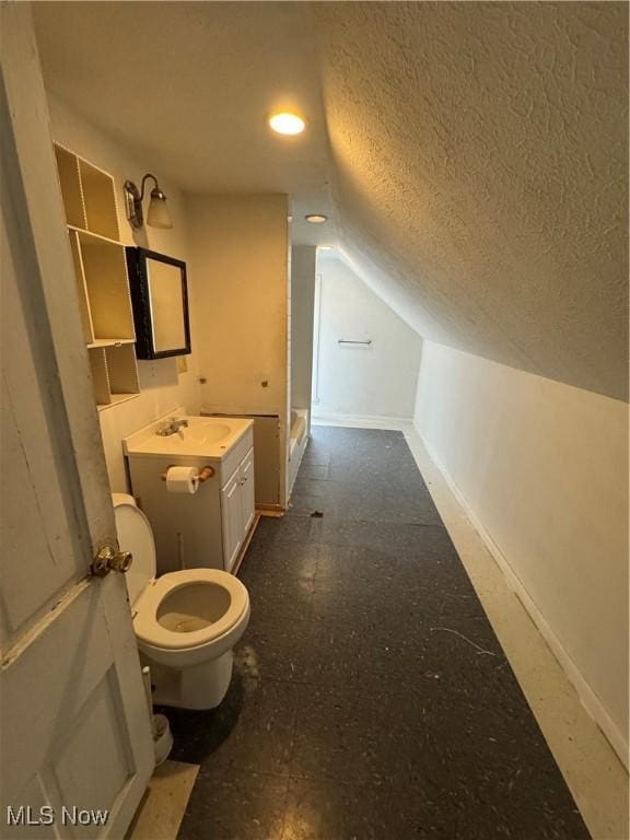 bathroom featuring lofted ceiling, vanity, toilet, and a textured ceiling