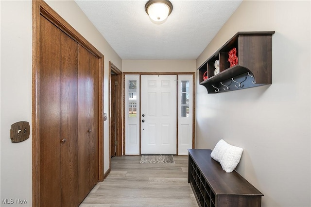 doorway to outside featuring a textured ceiling and light wood-type flooring