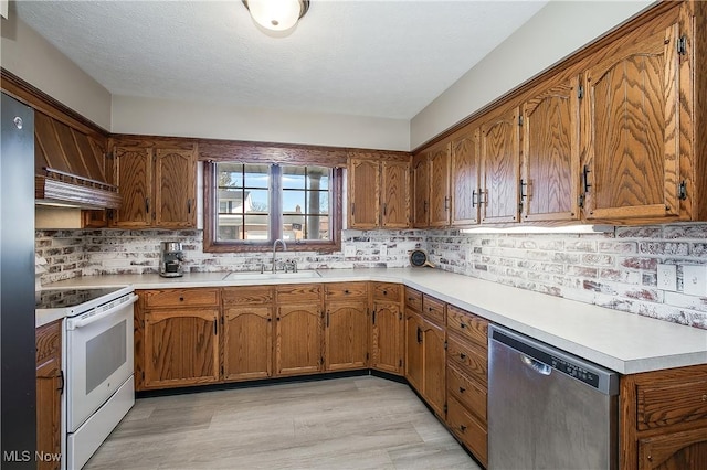 kitchen featuring dishwasher, sink, backsplash, light hardwood / wood-style floors, and electric stove