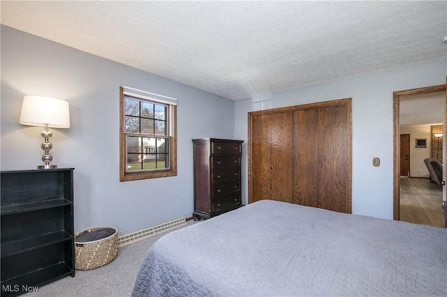 bedroom featuring a baseboard heating unit, a closet, and a textured ceiling