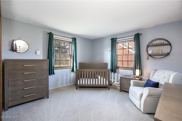 bedroom with light carpet, a crib, and a textured ceiling