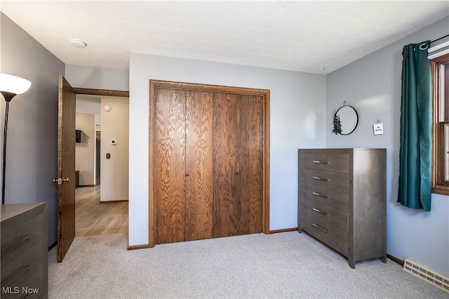 bedroom with light colored carpet, a closet, and a textured ceiling