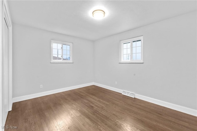 spare room with a healthy amount of sunlight and dark hardwood / wood-style floors