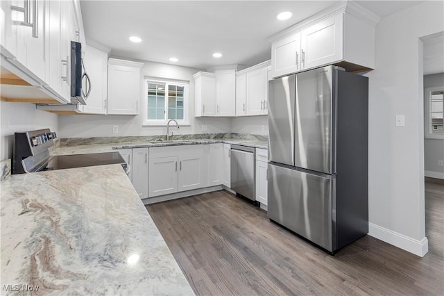 kitchen with dark hardwood / wood-style floors, sink, white cabinets, light stone counters, and stainless steel appliances