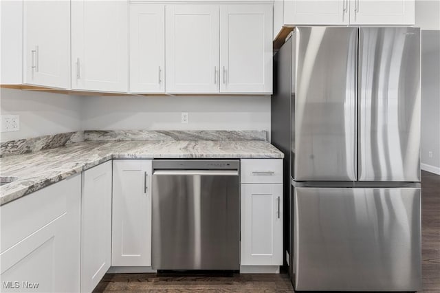 kitchen with white cabinetry, appliances with stainless steel finishes, dark wood-type flooring, and light stone counters