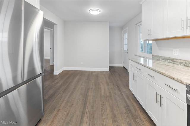 kitchen with light stone counters, dark hardwood / wood-style flooring, stainless steel fridge, and white cabinets