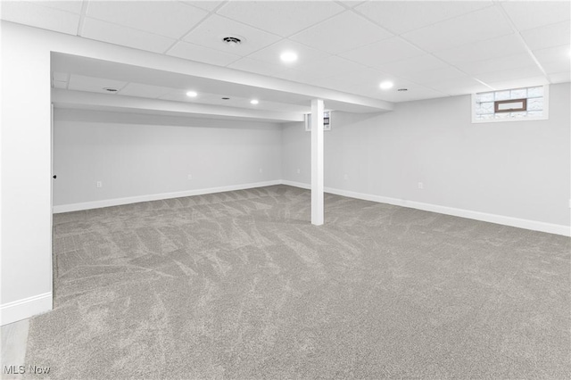 basement with a paneled ceiling and carpet floors