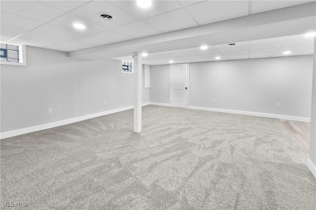 basement with carpet, a wealth of natural light, and a paneled ceiling