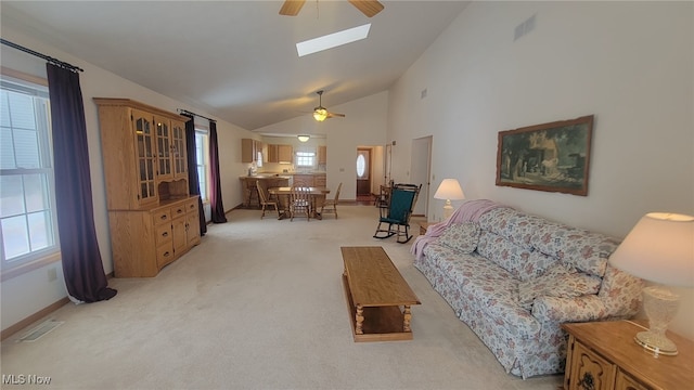 living room with light carpet, a skylight, high vaulted ceiling, and ceiling fan