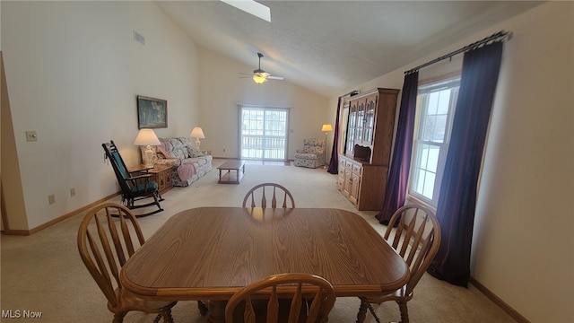 dining room with ceiling fan, light colored carpet, a healthy amount of sunlight, and high vaulted ceiling