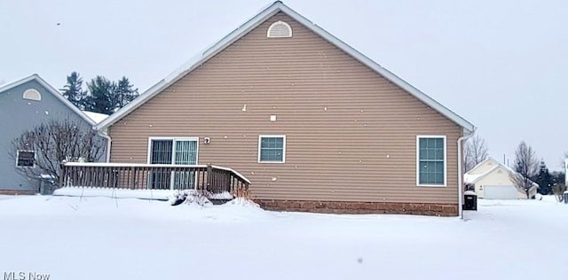 snow covered house with a wooden deck