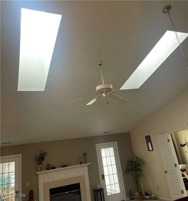 interior details with a ceiling fan and a tiled fireplace