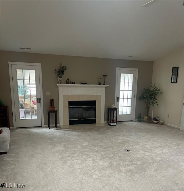 unfurnished living room featuring baseboards, visible vents, a fireplace, and carpet flooring