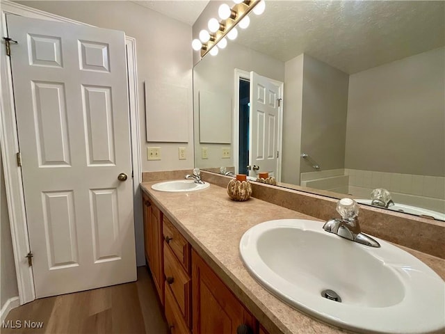 721 Winding Way, Akron, OH 44313 - bathroom with wood finished floors, a textured ceiling, double vanity, and a bathtub