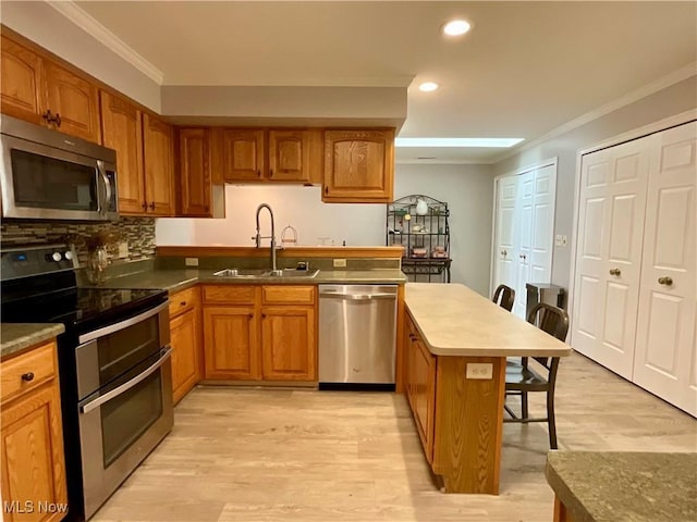 721 Winding Way, Akron, OH 44313 - kitchen with stainless steel appliances, a sink, ornamental molding, brown cabinets, and a kitchen bar
