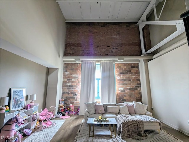 living room with hardwood / wood-style flooring, brick wall, and a high ceiling