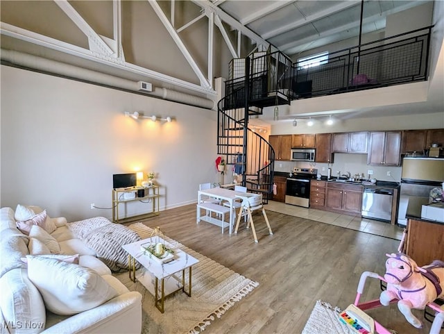 kitchen with sink, a high ceiling, light hardwood / wood-style floors, stainless steel appliances, and track lighting