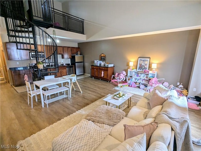 living room featuring a towering ceiling and light hardwood / wood-style flooring