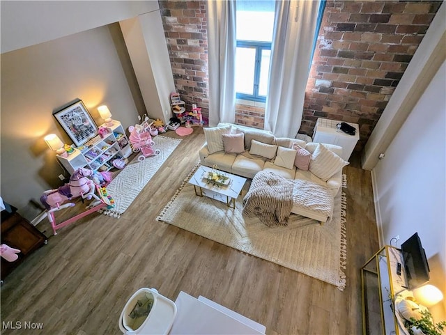 living room featuring hardwood / wood-style flooring and brick wall