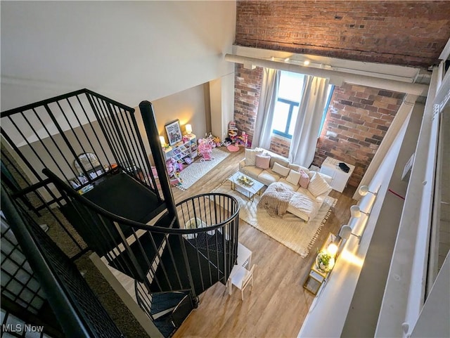 staircase with hardwood / wood-style floors and brick wall